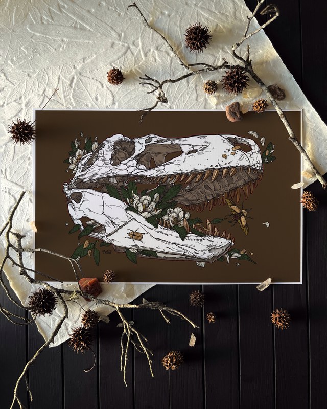 Print of a tyrannosaur skull with magnolia blossoms and beetles on a brown ground, laid on dark wood with pine cones and twigs, by Stacia Baldwin.
