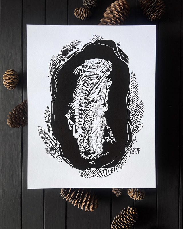 Black and white print of two small skeletons curled together inside a burrow, framed by ferns, by Stacia Baldwin.
