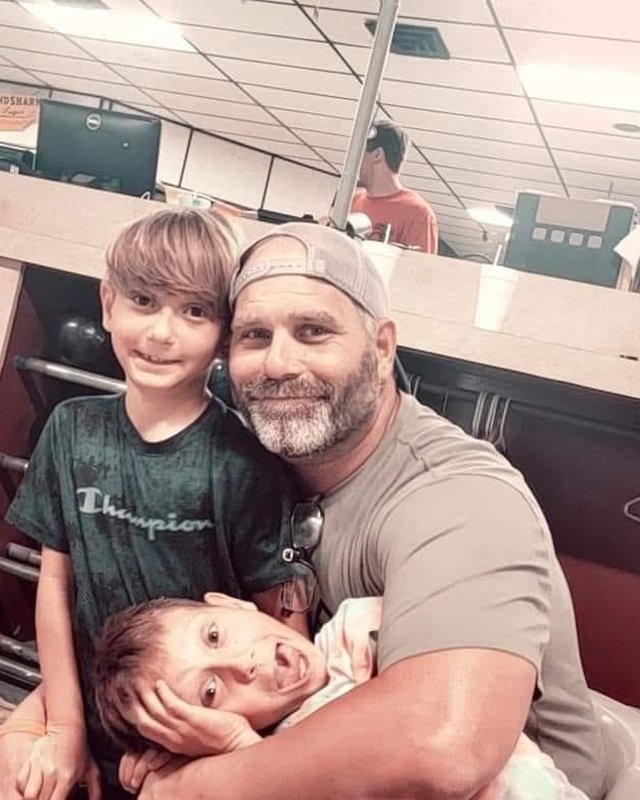 Terry Frank hugging his two kids at a bowling alley.