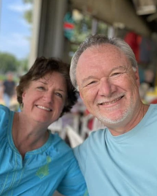 Scott and Laura Garrett seated together outdoors under an open shelter.