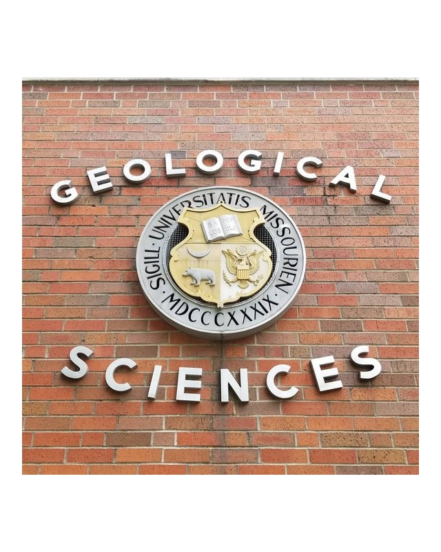 The Geological Sciences sign and university seal on the brick face of the building.