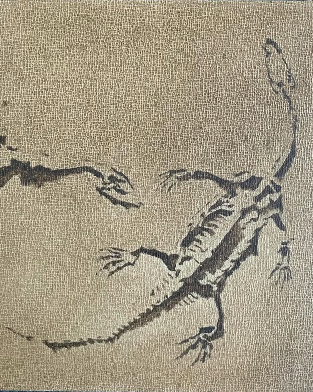 Ink drawing of a long-tailed reptile reaching toward a rock, on textured paper, by Anne Herrero.