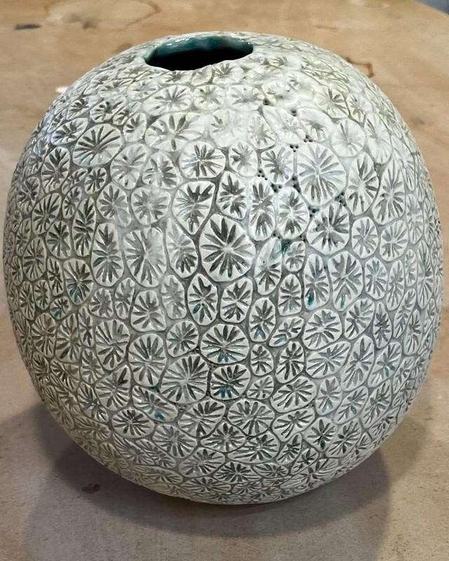 A round ceramic vessel covered in pale star shaped coral patterns, by Shoshana Parry.