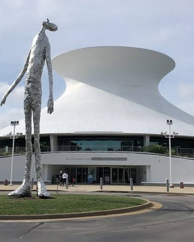 The James S. McDonnell Planetarium with a tall figure sculpture standing in front of it.