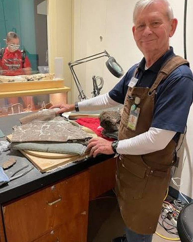 Woody, a Science Center volunteer, working on a fossil slab at the prep lab bench.