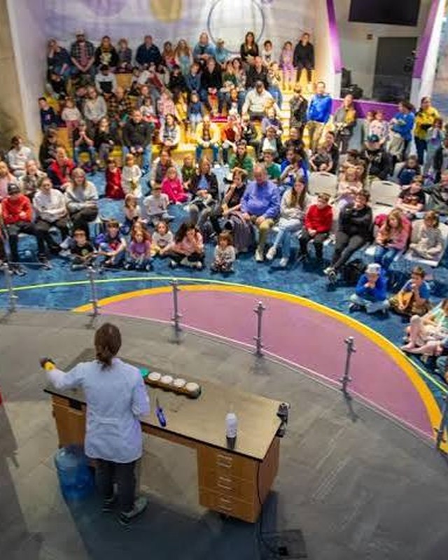 A presenter on the Energy Stage in front of a full audience of children and families.