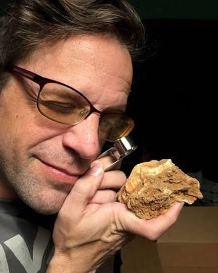 Asa Kaplan examining a fossil with a loupe.