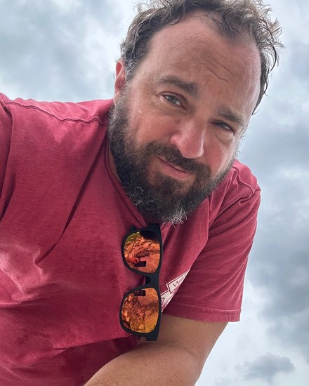 Jon Porter outdoors, with a rock outcrop reflected in the sunglasses at his collar.
