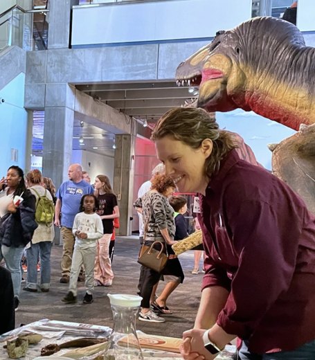 Abby Lee showing fossils to two children and their mother in the Saint Louis Science Center atrium.