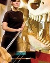 Nicki Mizell beside Lola, the T. rex skull sculpture.